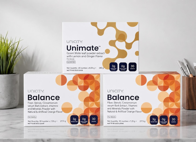 May include: Three white rectangular boxes of Unicity dietary supplements. One Unimate box features gold abstract shapes, while two Balance boxes display orange circular patterns. Each box lists ingredients, 3g fiber, 0g sugar, and 30 sachets.