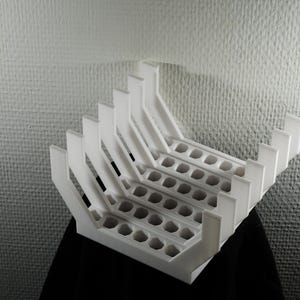 May include: A white 3D printed storage rack featuring five parallel U-shaped channels with a series of circular cutouts along the base of each section, designed to hold multiple items in an upright, organised, and vertical position.