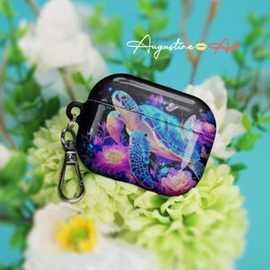 May include: A black protective case for wireless earbuds featuring a vibrant graphic of a sea turtle swimming among colorful flowers and butterflies. The case includes a silver metal carabiner clip attached to the side and the text Augustine Art.