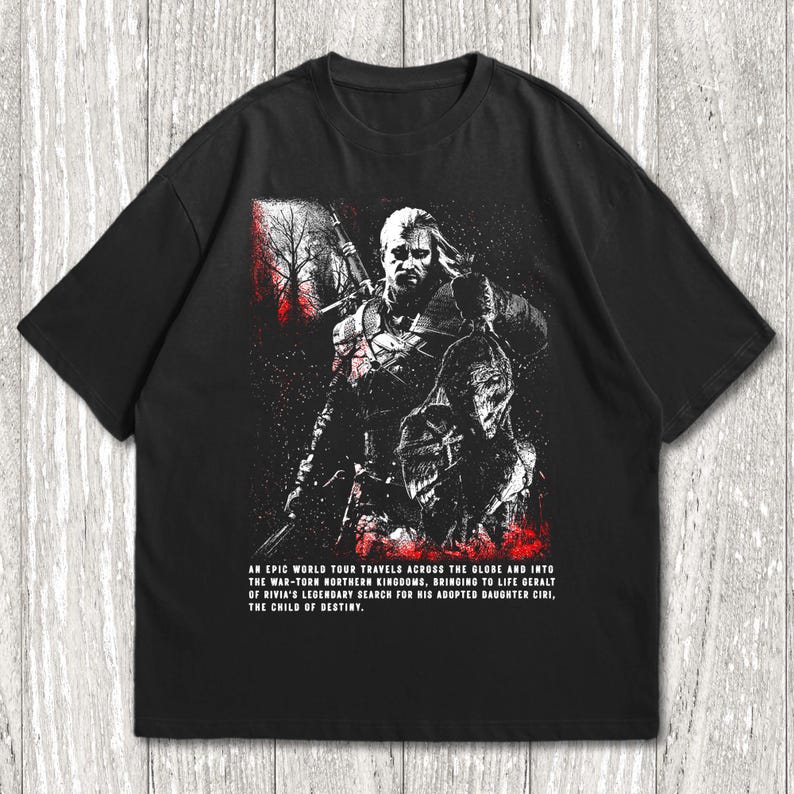 May include: A black short-sleeved t-shirt featuring a graphic illustration of a warrior with a sword. The design includes red accents and text that reads: AN EPIC WORLD TOUR TRAVELS ACROSS THE GLOBE AND INTO THE WAR-TORN NORTHERN KINGDOMS, BRINGING TO LIFE GERALT OF RIVIA'S LEGENDARY SEARCH FOR HIS ADOPTED DAUGHTER CIRI, THE CHILD OF DESTINY.