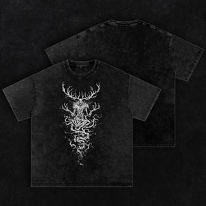 May include: A black acid-wash t-shirt featuring a white graphic print of a skeletal, antlered creature with long, spindly fingers and a swirling, root-like lower body. The design is centered on the chest, while the back of the shirt is plain.