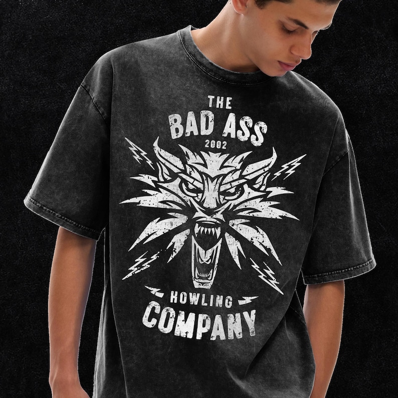 Peut inclure: Un t-shirt gris anthracite d&eacute;lav&eacute; &agrave; l'acide avec un motif blanc vieilli repr&eacute;sentant une t&ecirc;te de loup hurlant et des &eacute;clairs. Le texte THE BAD ASS 2002 HOWLING COMPANY est imprim&eacute; en lettres grasses et us&eacute;es sur la poitrine du v&ecirc;tement.