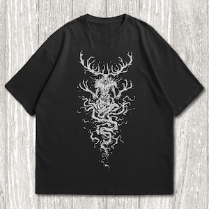 May include: A black short-sleeved t-shirt featuring a white graphic print on the front. The design depicts a skeletal, antlered creature with long, spindly fingers and a flowing, root-like lower body that extends downward in a swirling pattern.