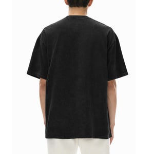 Peut inclure: Un t-shirt &agrave; manches courtes de couleur noir d&eacute;lav&eacute; avec une encolure ronde. Le v&ecirc;tement pr&eacute;sente une coupe d&eacute;contract&eacute;e et une apparence unie et uniforme sur le dos, fabriqu&eacute; dans un tissu semblable au coton avec une texture l&eacute;g&egrave;rement d&eacute;lav&eacute;e.
