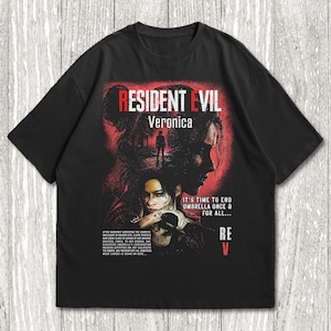 May include: A black short-sleeve t-shirt featuring a graphic print with the text Resident Evil Veronica. The design includes a red and black illustration of a character, the phrase It's time to end Umbrella once & for all, and small text.
