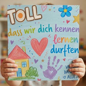 Pode incluir: Um cartão retangular azul-claro com o texto TOLL dass wir dich kennen lernen durften em letras coloridas. O design inclui uma casa amarela desenhada à mão com telhado vermelho, um grande coração rosa, uma impressão de mão roxa e estrelas.