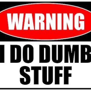 May include: A rectangular sign with a black border, featuring the words "WARNING" in white on a red oval, above "I DO DUMB STUFF" in bold black letters on a white background. The sign is designed to be eye-catching.