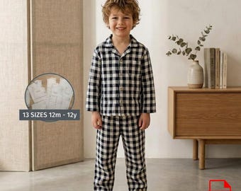 May include: A child wearing a black and white checkered pajama set. The long-sleeved shirt and pants are buttoned up. The image includes text that reads "13 SIZES 12m - 12y".