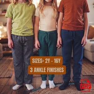 May include: Three pairs of pants worn by children. The left pair is charcoal gray, the center pair is dark green with a drawstring waist, and the right pair is navy blue. Text on the image reads: SIZES= 2Y - 16Y and 3 ANKLE FINISHES.