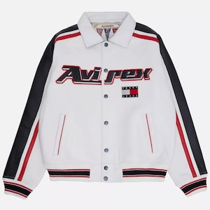 May include: White leather jacket with black sleeves and red detailing. The jacket features the "Avirex" logo in red and black, and a "Tommy Jeans" patch. It has a button-up front and striped detailing on the cuffs and hem.