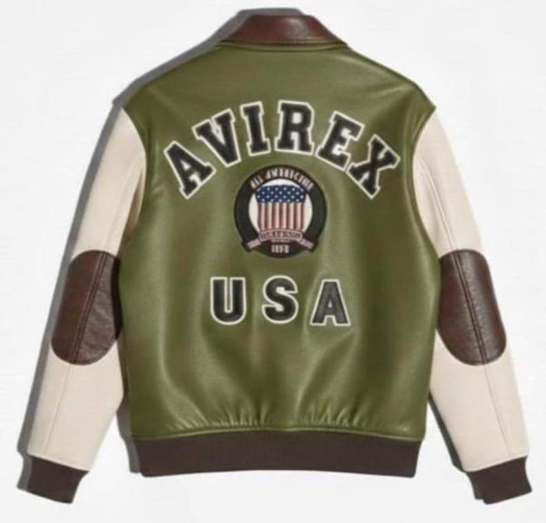 Puede incluir: Chaqueta universitaria Avirex USA verde y crema. La parte trasera de la chaqueta presenta la palabra "AVIREX" sobre un parche circular con un dise&ntilde;o de bandera estadounidense y la palabra "USA" debajo. Detalles en cuero marr&oacute;n en el cuello, codos y pu&ntilde;os.