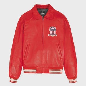 May include: A vibrant red leather jacket with a collar and zip fastening. It has a patch on the chest displaying an American flag design and the text "AVIREX". The cuffs and hem are detailed with white and red stripes.