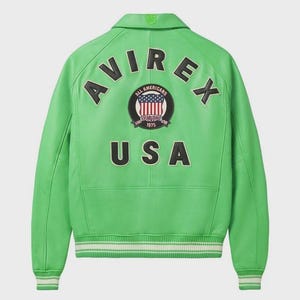 May include: A vibrant green leather jacket featuring the word "AVIREX" across the shoulders, and "USA" below a circular emblem. The emblem displays the American flag and the words "ALL AMERICANS ESTABLISHED 1975". The jacket has a collar and white and green striped cuffs.