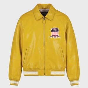 Puede incluir: Chaqueta de cuero amarillo mostaza con cierre de cremallera, cuello y pu&ntilde;os y dobladillo acanalados. Cuenta con un parche en el pecho con el texto "AVIREX" y un dise&ntilde;o con colores rojo, blanco y azul. Un estilo cl&aacute;sico de chaqueta bomber.