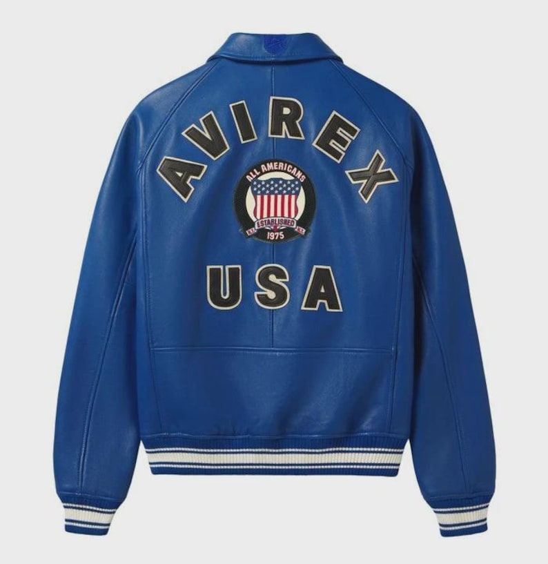 May include: A vibrant blue leather jacket with the word "AVIREX" arched across the shoulders. Below, the word "USA" is displayed. A circular patch with the words "ALL AMERICANS" and "ESTABLISHED 1975" is centered. The jacket has white and black striped cuffs.