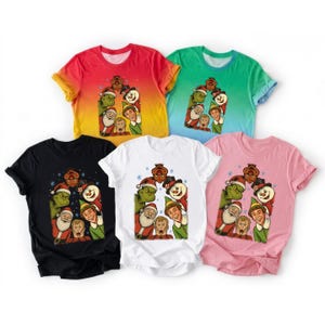 May include: Five short-sleeve t-shirts in red-orange gradient, green gradient, black, white, and pink. Each shirt features a central graphic print of characters from holiday movies including the Grinch, Santa, Buddy the Elf, and Kevin McCallister.