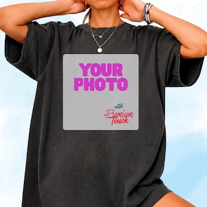 May include: A charcoal grey short-sleeve t-shirt featuring a large light grey square graphic on the chest. The graphic displays the text "YOUR PHOTO" in bold pink letters, followed by the smaller blue and red text "with Premium Touch".