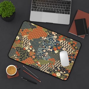 Könnte beinhalten: Rechteckiges Mauspad mit japanisch inspiriertem Design. Es zeigt florale, Wellen- und geometrische Muster in Rot, Orange, Grün und Weiß auf marineblauem Hintergrund. Eine weiße Computermaus liegt darauf.
