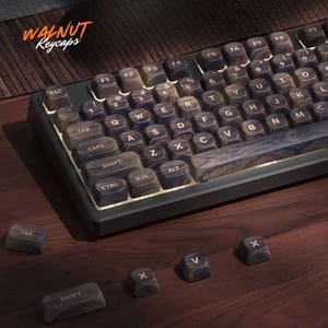May include: A mechanical keyboard featuring dark brown walnut wood keycaps with a visible natural grain pattern and gold-colored lettering. The text WALNUT Keycaps is visible in the upper left corner. Several loose keycaps are placed in the foreground.