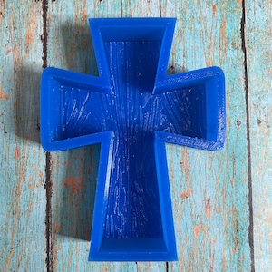 May include: A blue silicone mold shaped like a cross with a wood grain texture. The mold is designed for making crafts or decorations.