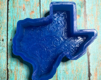 May include: A blue silicone mold shaped like the state of Texas with a decorative floral pattern inside.