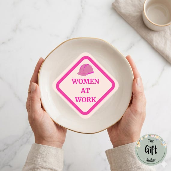 A ceramic trinket dish with witty 'Women at Work' corporate humor — the kind of desk piece that sparks a knowing laugh without being a generic mug or sticker.