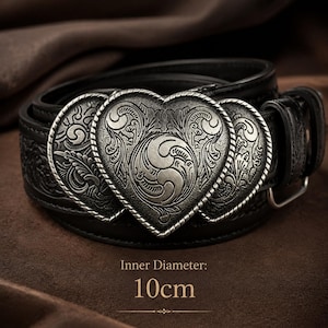 May include: A black belt featuring a large, silver-toned heart-shaped buckle with intricate embossed scrollwork patterns. The belt strap also displays a matching embossed texture. Text on the image indicates an inner diameter of 10cm.