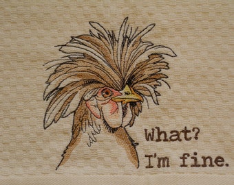May include: Embroidered kitchen towel featuring a whimsical chicken with a large, brown feathered crest and a quizzical expression. The text "what? I'm fine" is embroidered below the chicken. The towel has a textured, cream-colored background.