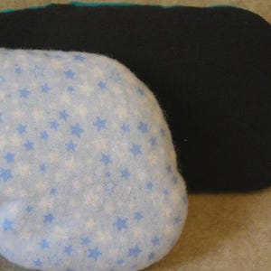 May include: Two eye masks. One is light blue with white and blue stars. The other is black. The edges of the light blue mask are trimmed with teal fabric. The masks are designed to block out light.