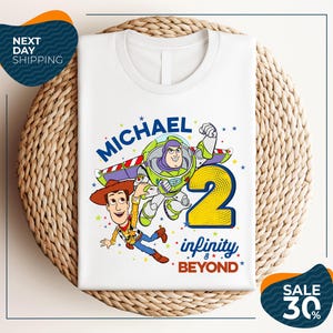A white t-shirt with a graphic design featuring Buzz Lightyear and Woody from Toy Story, along with the text "Michael 2 Infinity Beyond".