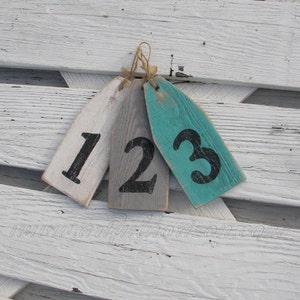 May include: Three wooden tags with the numbers 1, 2, and 3 painted on them. The tags are painted in white, gray, and teal.