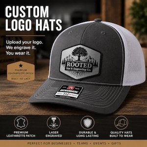 May include: A grey and white trucker hat with a custom logo patch. The patch features a tree and mountain design with the text "ROOTED Hat & Engraving Co." The hat has a curved brim and an adjustable strap. The text "CUSTOM LOGO HATS" is at the top.