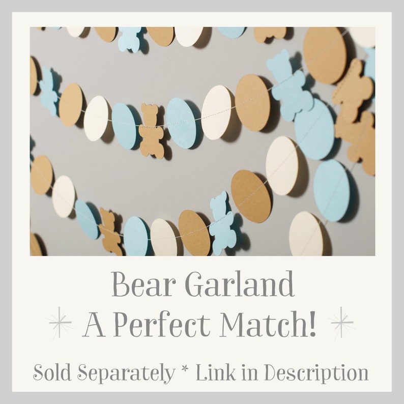 May include: A garland of alternating blue and brown paper circles with small brown bear cutouts hanging from a string. The text "Bear Garland * A Perfect Match! * Sold Separately * Link in Description" is at the bottom of the image.