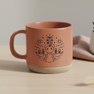 Peut inclure: Une tasse en c&eacute;ramique couleur terre cuite avec une finition mouchet&eacute;e et une base beige clair. La tasse pr&eacute;sente un dessin au trait noir d'un personnage fantaisiste sur un chemin avec des fleurs, des &eacute;toiles et des nuages. La tasse a une grande anse.