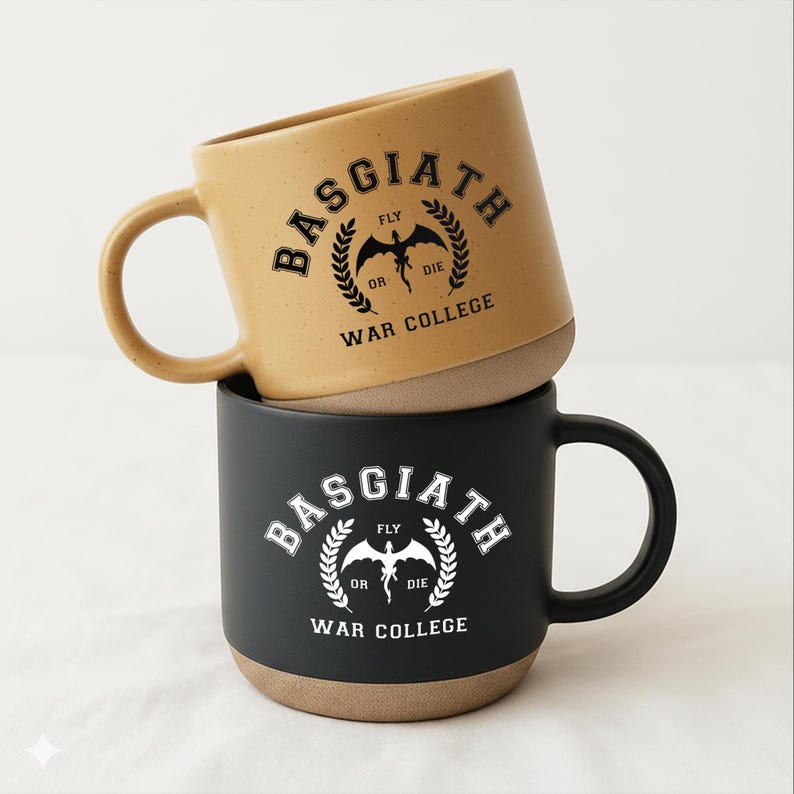 May include: Two ceramic mugs stacked vertically. The top mug is tan with black text reading BASGIATH WAR COLLEGE and FLY OR DIE with a dragon graphic. The bottom mug is matte black with white text and a matching dragon graphic. Both have handles.