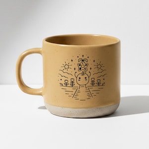 Peut inclure: Mug en c&eacute;ramique beige avec une illustration en noir et blanc. Le dessin repr&eacute;sente un personnage souriant avec une t&ecirc;te en forme d'&eacute;toile, entour&eacute; de fleurs, d'&eacute;toiles et de nuages. Le bas de la tasse est beige clair.