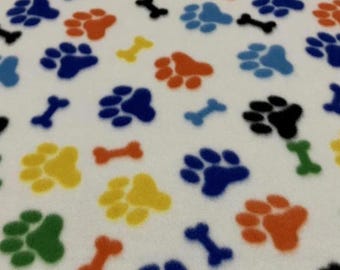 Zampe e ossa con stampa arcobaleno - Materiale in pile morbido e anti-pilling, venduto tagliato su misura.