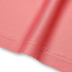 Op de afbeelding: Een effen koraalroze stof met een fijne, uniforme mesh-textuur. Het materiaal is voorzien van een horizontale zoom met dubbele stiksels langs de onderrand, wat zorgt voor een nette afwerking. De stof is gedrapeerd met zachte verticale plooien.