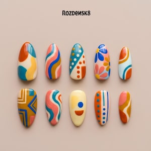 May include: A set of ten almond-shaped press-on nails featuring the brand name Rozdensk8 at the top. Each nail displays a unique, colorful design with patterns including wavy lines, geometric shapes, dots, and floral motifs in blue, orange, pink, and cream.