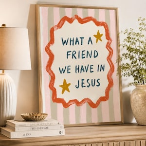 May include: A framed wall art print featuring vertical light pink and beige stripes. In the center, a wavy orange border surrounds the dark blue text "WHAT A FRIEND WE HAVE IN JESUS" with two yellow stars positioned above and below the text.