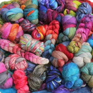 May include: A vibrant assortment of colorful yarn in various textures and hues. The image showcases a mix of pink, orange, blue, green, and purple fibers, perfect for crafting projects. The yarn is arranged in a visually appealing, textured pile.