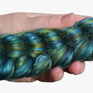 Peut inclure: Une pelote de fil teinte &agrave; la main dans des tons de bleu sarcelle, vert et or. Le fil est torsad&eacute; et a une texture duveteuse.