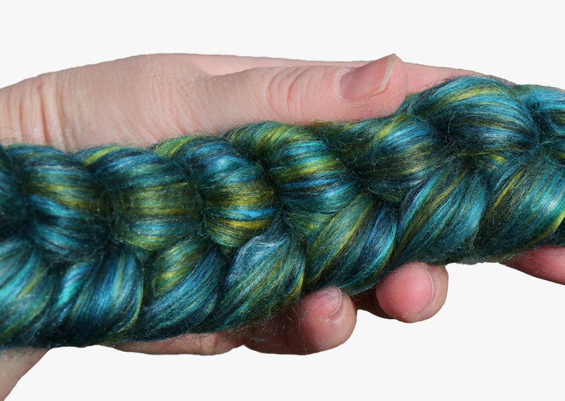 Peut inclure: Une pelote de fil teinte &agrave; la main dans des tons de bleu sarcelle, vert et or. Le fil est torsad&eacute; et a une texture duveteuse.