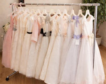 Exquisitos vestidos de damita de honor, diseñados por Joan Calabrese, están disponibles en marfil, rosa palo y blanco. Están confeccionados en organza, satén y tul.