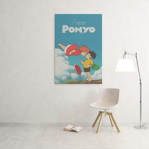 May include: A framed poster featuring the animated film "Ponyo." The poster has a light blue background with the title "Ponyo" in white. The artwork depicts two animated characters, one in a red dress and the other in a yellow shirt.