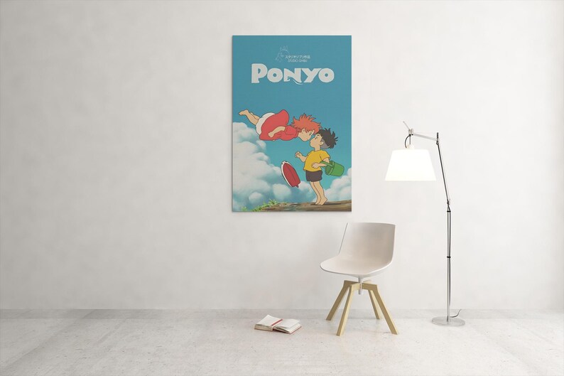 May include: A framed poster featuring the animated film "Ponyo." The poster has a light blue background with the title "Ponyo" in white. The artwork depicts two animated characters, one in a red dress and the other in a yellow shirt.