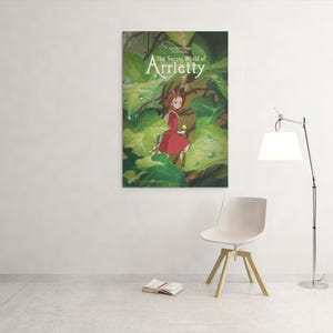 May include: A framed poster of "The Secret World of Arrietty" hangs on a white wall. The poster features a young girl in a red dress amidst lush green foliage. A white chair, a book, and a lamp are in the foreground.
