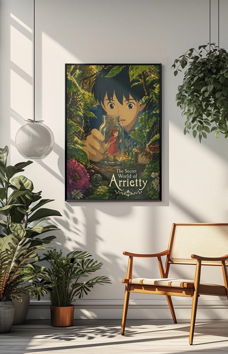 May include: A framed poster featuring the animated film "The Secret World of Arrietty." The artwork depicts a young boy holding a jar containing a tiny girl in a red dress, surrounded by lush green foliage. The poster is displayed on a white wall.