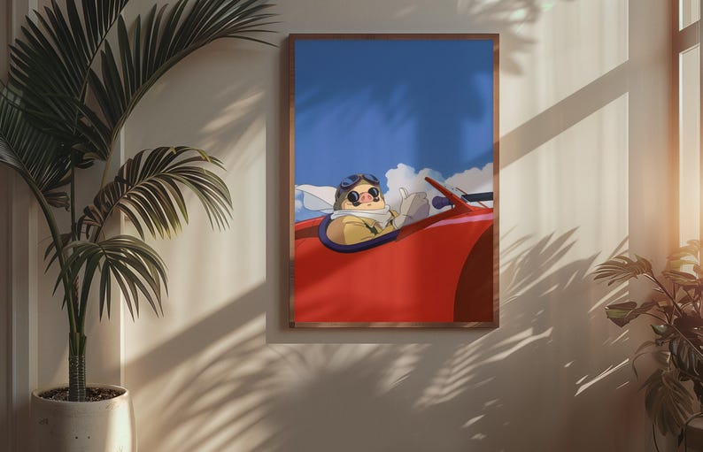 May include: A framed art print featuring an animated character in a red convertible against a blue sky with clouds. The character wears goggles and a scarf. The artwork is displayed on a wall with a potted plant.