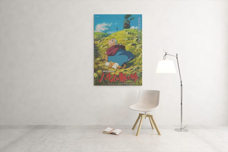 May include: A framed poster featuring a scene from an animated film. The artwork depicts a character in a red cloak and blue dress sitting on a grassy hill. Japanese text is visible at the bottom of the poster.